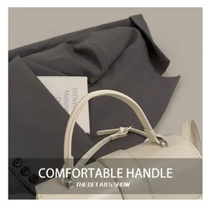 Detail of cream leather handbag showing elegant stitching and silver adjustable buckle