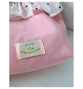 Close-up of pink canvas bag with floral embroidery and white ruffled polka dot trim