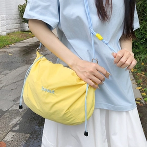 Detail of yellow nylon drawstring bag with blue embroidery and adjustable strap slider