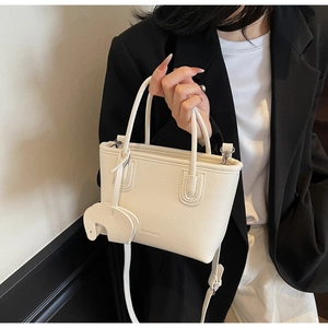 Detail of cream white lychee leather texture and cute elephant charm on a handbag