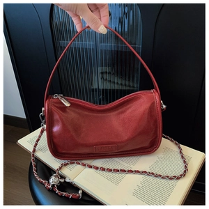 Close-up of red oil-wax leather texture and silver chain strap on crescent bag