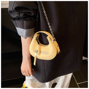 Chic yellow lychee texture half-moon bag worn with metal chain and black suit detail