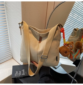 Détail du sac seau en toile avec bandoulière réglable et breloque ours en peluche