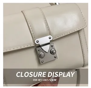 Detailed view of the silver metallic buckle and fine leather texture of the square bag