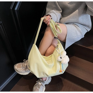 Dettaglio borsa hobo a quadretti giallo chiaro con ciondolo orsetto su scale in legno