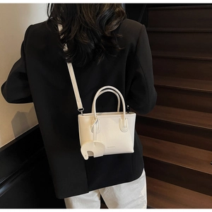 White litchi pattern small handbag with a cute elephant charm shown on a model