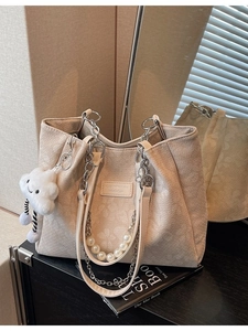 Off-white embossed tote bag with pearl chain straps and cloud charm in a lifestyle setting