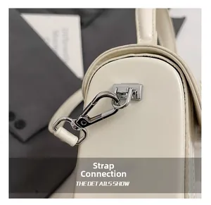 Detailed close-up of the silver lobster clasp and D-ring on the cream white handbag