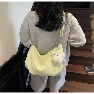 Dettaglio della borsa hobo in tela gialla a quadretti con un ciondolo a forma di coniglio