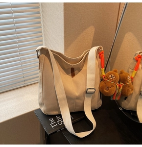 Détail du sac seau en toile avec bandoulière large, boucle argentée et breloque capybara