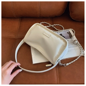 Detail shot of a cream-white pillow bag with silver chain strap and leather handle