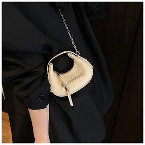Detail of cream crescent handbag with lychee texture and silver chain strap