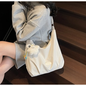 Detailed view of white checkered canvas hobo bag with cute plush bear charm on a model
