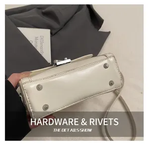 Detail showing silver protective metal rivets on the bottom of a cream leather handbag