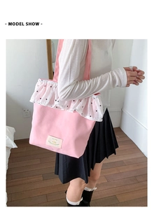 Model wearing a pink canvas tote bag with white lace trim and light green label detail