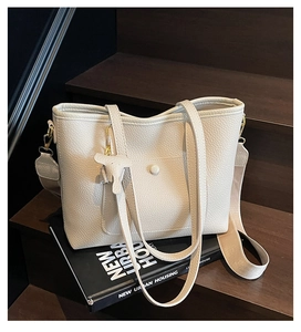 Detail of off-white lychee grain tote bag with canvas strap on a wooden staircase