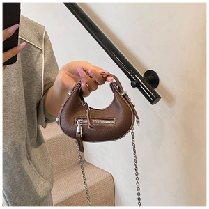 Close-up of brown litchi pattern leather mini handbag with silver chain and zipper