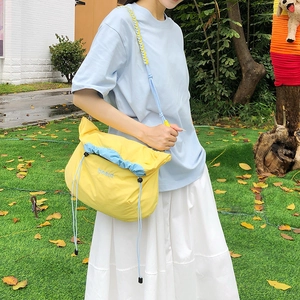 Detail of yellow nylon crossbody bag featuring blue drawstrings and beaut embroidery