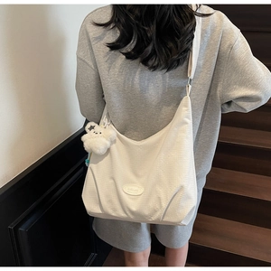 Close-up of white waffle texture canvas hobo bag with cute plush bear charm detail