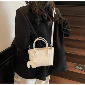 Detail view of mini white lychee leather handbag with a cute elephant charm