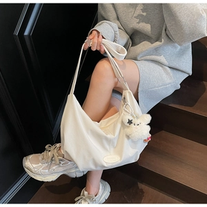 Dettaglio borsa hobo bianca con trama a nido d'ape e ciondolo a coniglio in peluche