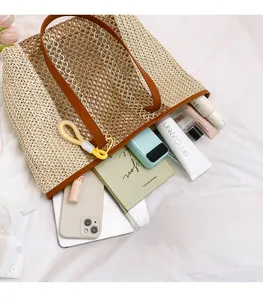 Macro view of beige straw woven tote bag showing large capacity and leather handles