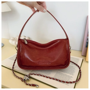 Detail of burgundy leather handbag with metallic ball chain and CEHEKA brand logo