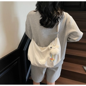 Vista posteriore di una borsa tote bianca a nido d'ape con ciondolo a coniglio sul modello