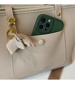 Detail of off-white lychee grain leather tote with smartphone pocket and elephant charm