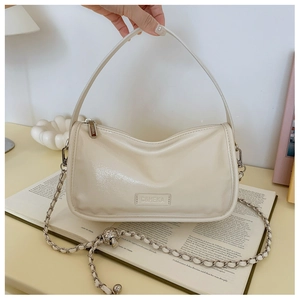 Detail of cream pillow bag showing smooth faux leather texture and gold chain strap