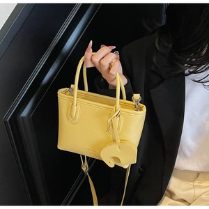 Close-up of a yellow lychee pattern leather handbag with an elephant charm detail