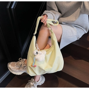 Detail of yellow checkered hobo bag with plush bear charm on adjustable strap