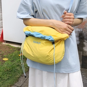 Detail of yellow and light blue nylon crossbody bag with beaut embroidery and drawstring
