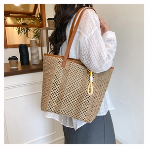 Large woven beach tote bag with leather straps and yellow tassel accessory on a model