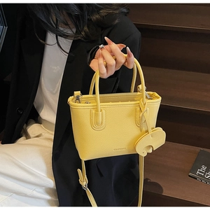 Detail of yellow lychee grain leather tote bag with SOLAR&MISS logo and elephant charm