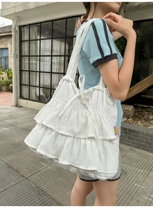 Detail showing white tiered ruffle fabric texture with drawstring bow on tote bag side