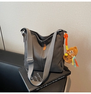 Vue détaillée du sac seau en toile grise avec logo en cuir et breloque ours
