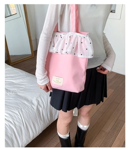 Detail of pink canvas tote bag featuring layered floral ruffles and a small woven label