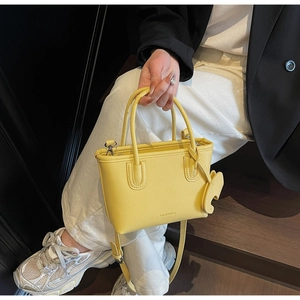 Detail view of yellow lychee texture mini bag with cute elephant charm and thin strap