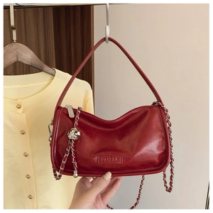 Detail of red wax leather crescent bag featuring silver chain and metal ball charm