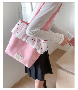Close-up of pink canvas tote bag with white floral lace trim and aesthetic patch label