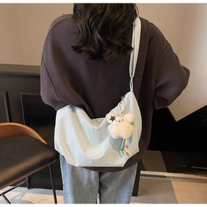 Dettaglio della borsa tote a scacchi celeste con ciondolo di peluche e patch del logo