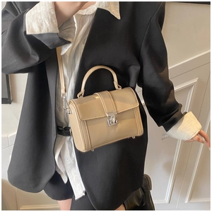 Detail of minimalist beige leather crossbody bag with silver hardware and handle
