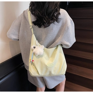 Detail of light green checkered canvas tote bag with adjustable strap and cute bear charm