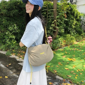 Detail of khaki nylon waterproof crossbody bag with yellow drawstring and beaut print