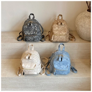 Detailed view of four mini backpacks featuring embossed textures and metal dual zippers