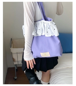 Lavender canvas tote bag with white floral lace ruffle detail and front label patch
