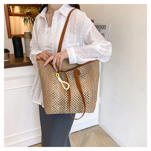 Detail of large woven beach tote featuring leather straps and decorative tassel on a model