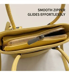 Close-up of silver metal zipper and yellow lychee grain leather on the stylish handbag
