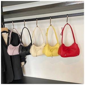 Detail view of colorful bow shoulder bags hanging on a rack showing textured PU leather